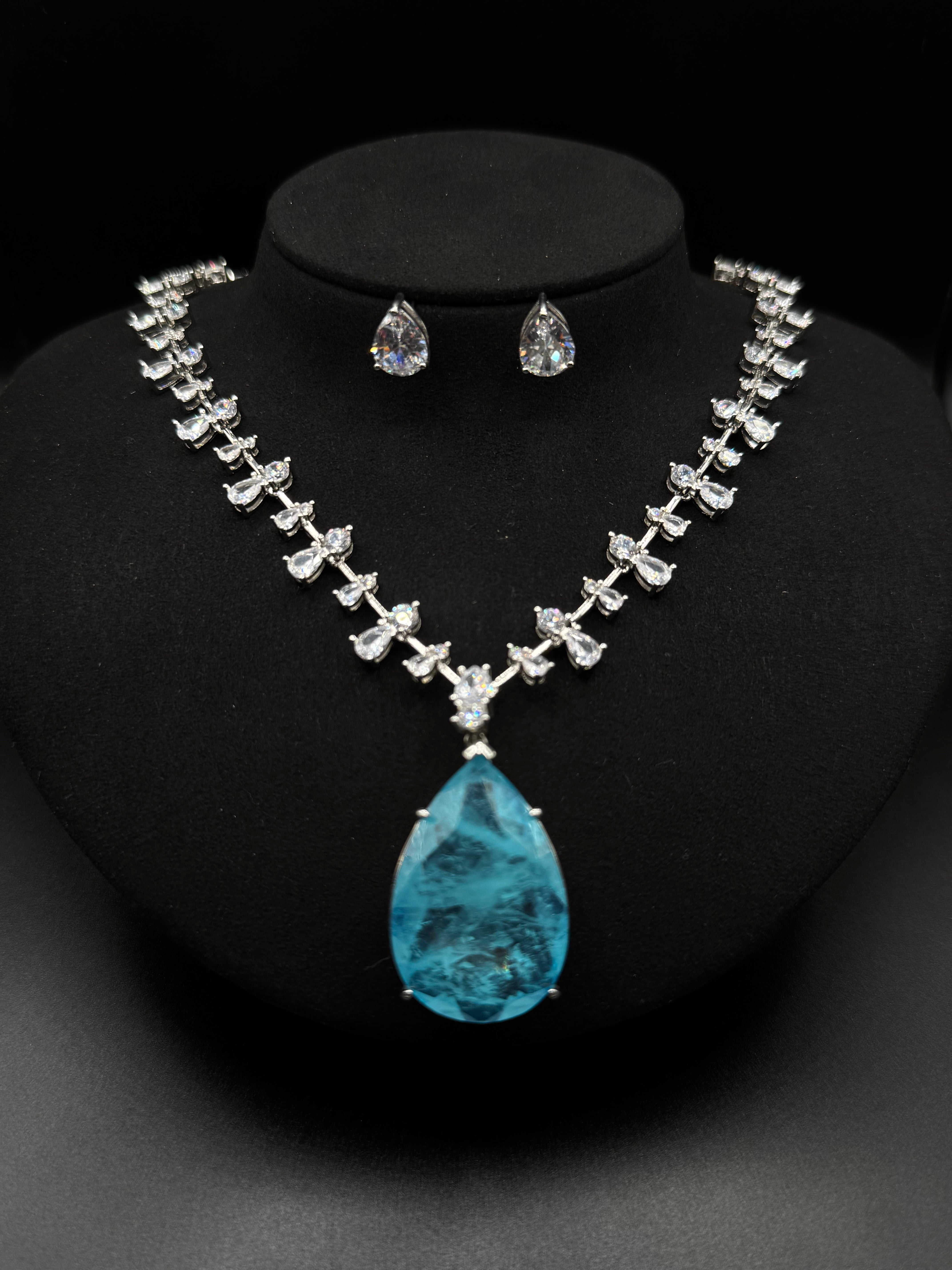 Luxury rhodium-plated jewelry set with a teardrop-shaped turquoise fusion stone pendant